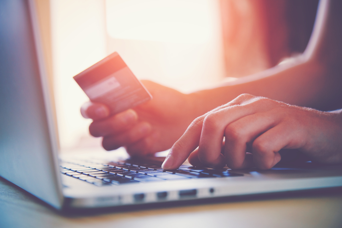 A person holding a credit card and using a laptop