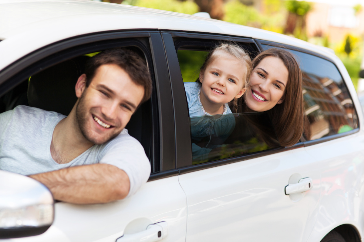 A family in a vehicle smiling while leaning out of the windows