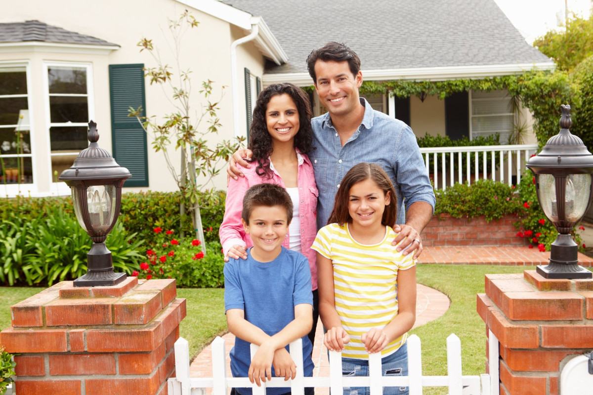 A smiling family in front of their house