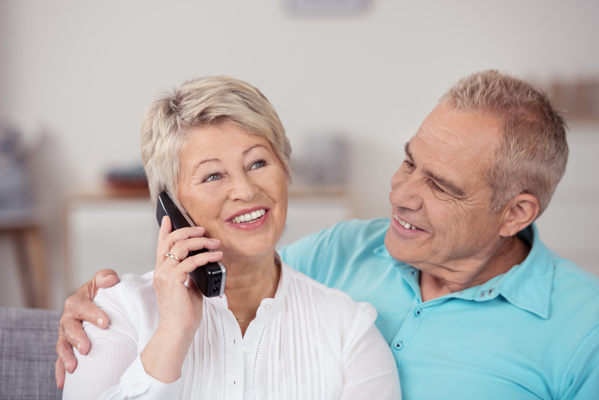 An elderly couple talking on the phone